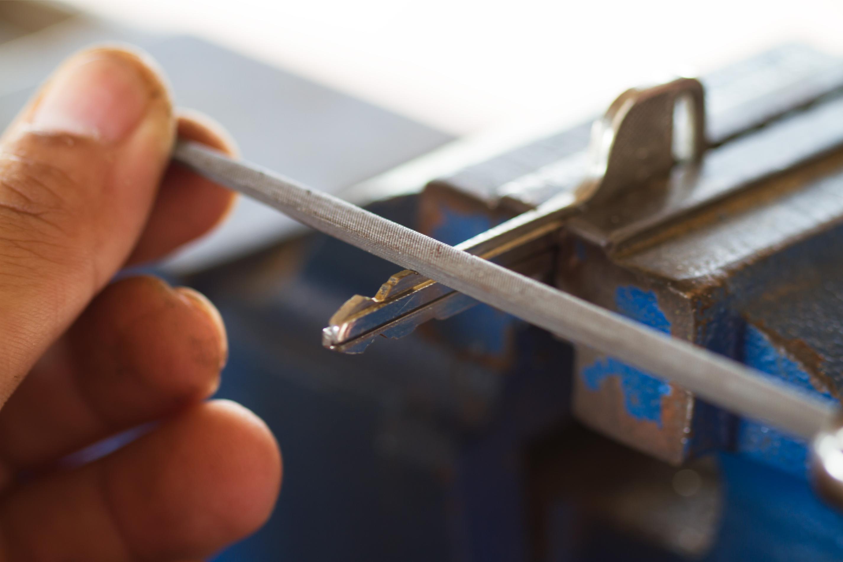 Locksmith using tools to cut a key for 24-hour emergency locksmith service in Cache Valley