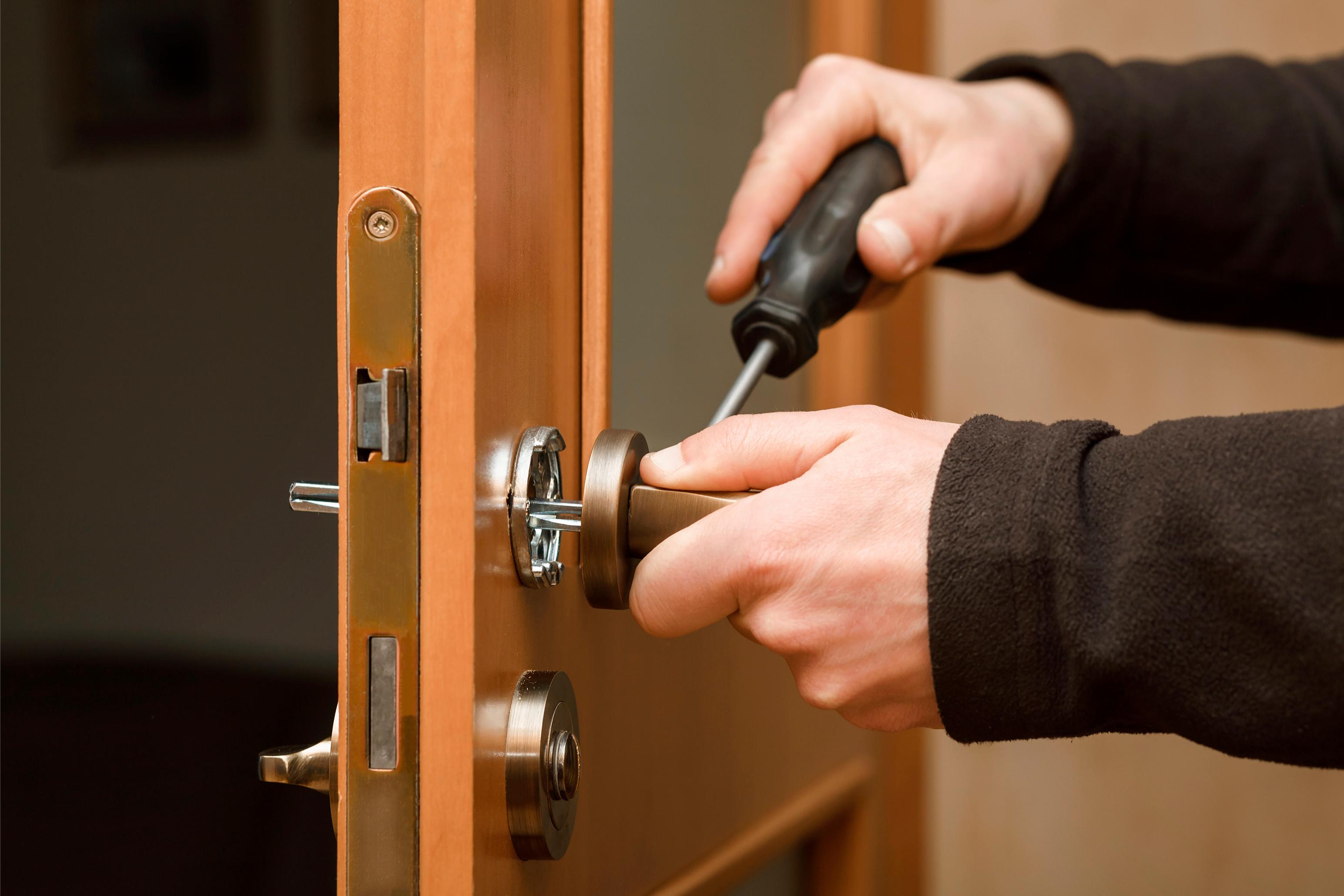 Person tightening a door knob with a screwdriver for commercial locksmith services in Cache Valley, UT